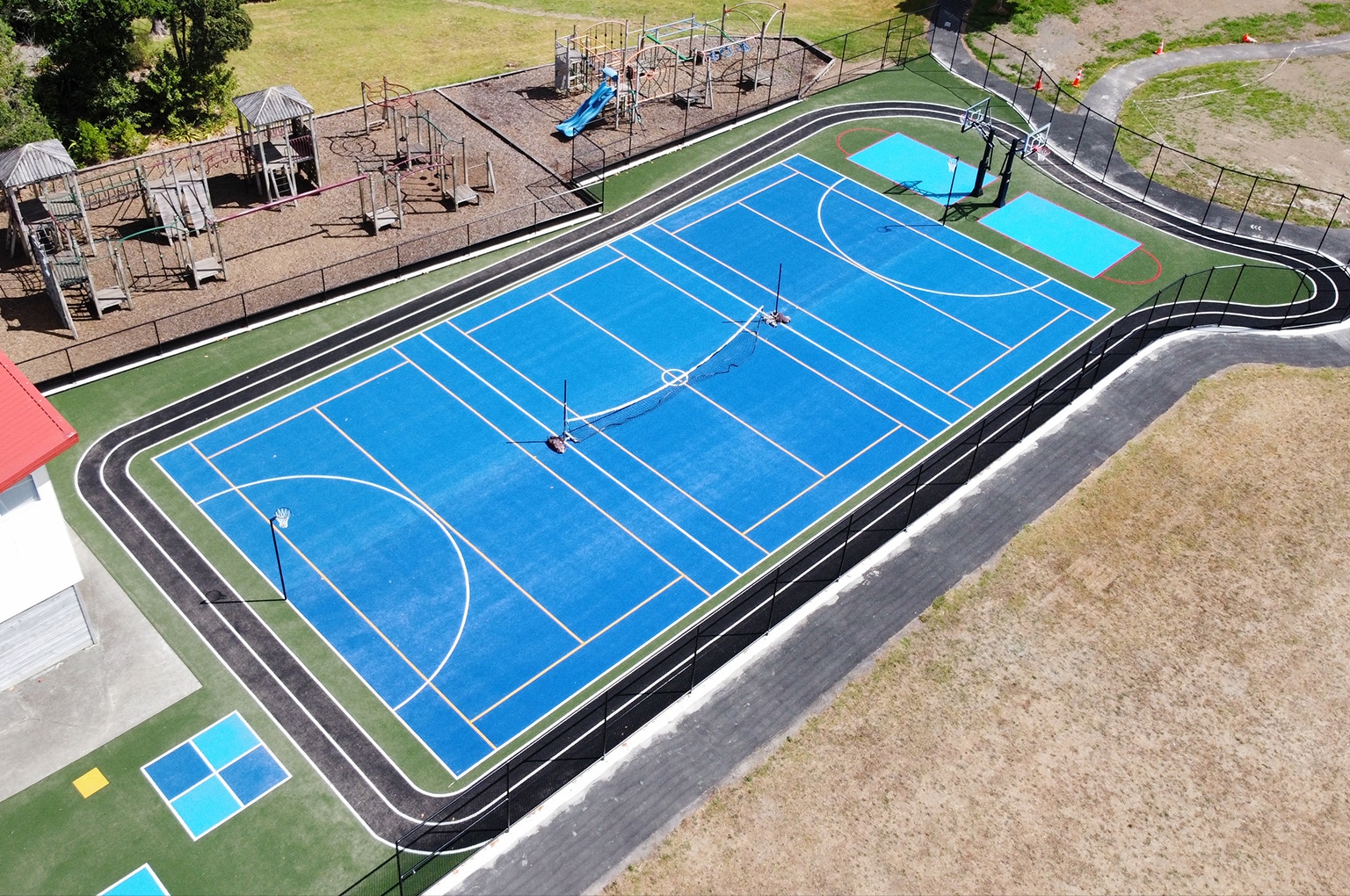New multi-sport court with artificial turf by Game On Turf in Auckland, New Zealand, featuring basketball, netball, and running track.