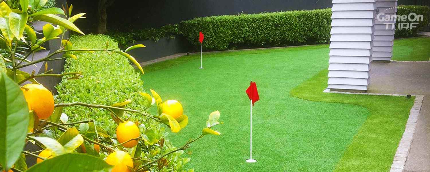 Game On Turf artificial putting green in a New Zealand garden, showcasing vibrant green synthetic turf, red flag pins, edged by hedges and a paved path